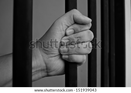 Hand of the prisoner on a jail bar