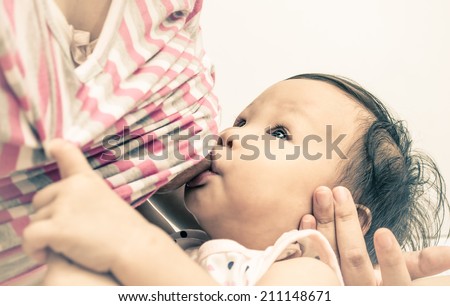 Asian mom breast feeding her baby girl with vintage filter.