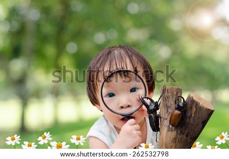 Little girl looking rhino beetle in garden