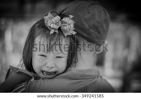 Little girl crying between stranger holding ,black and white col