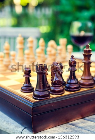 Chess board game with a glass of wine on a wooden table in a french vineyard during summer time