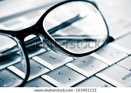 Prescription vision glasses on an aluminum laptop. Detail. Modern technology concept