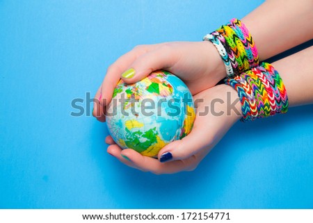Young girl holding the Earth., wearing loom rubber bracelets. Close up. Young fashion concept