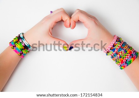 Young girl holding hands in a heart shape wearing loom bracelets Close up Young fashion concept Young girl holding hands in a heart shape wearing loom bracelets Close up Young fashion concept