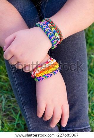 Young girl wearing loom bracelets, Young fashion, outdoors, friendship, crafts, and lifestyle concept. Bright tones. Shallow depth of field.