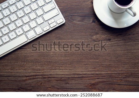 Close up detail of an aluminum keyboard on a vintage wooden desk. Technology, finance, business, baking, online shopping and education concept. Natural window light.