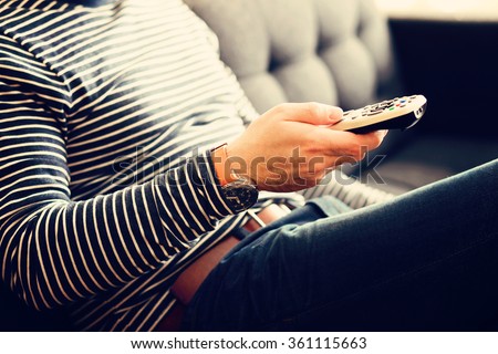 Young man holding a tv cable remote, watching tv. Life style, entertainment, young people. fashion, design  and interior concept