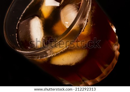 glass with dark liquid full with ice cubes on white background