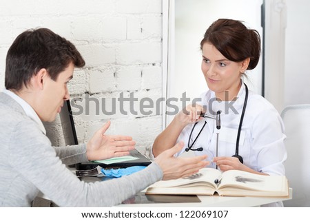 Doctor joshing patient with reflex hammer and nail