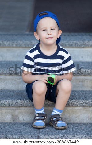 Lovely kid sitting on the stairs and waiting for a walk