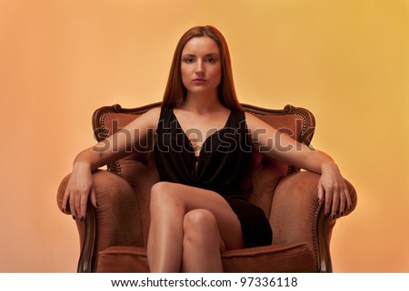 Woman sitting on a chair in the evening gown and in brown tones