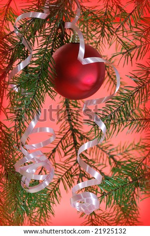 red Christmas ball with ribbon between fir tree branches