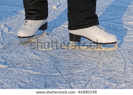 skater\'s legs standing on winter ice rink