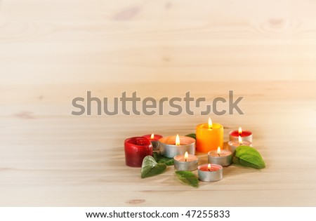 burn scented candles  and green leaves on wood background  with copyspace