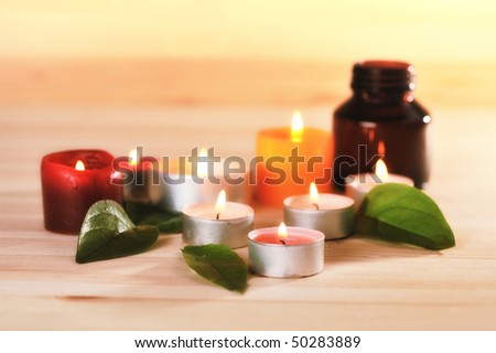 burn scented candles  with brown bottle with essential oil on wood background