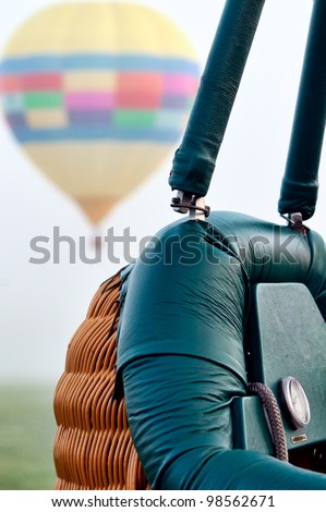 Close up of a hot air balloon basket with a hot air balloon floating in the background