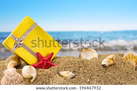 Gold gift box on sand with summer sea background