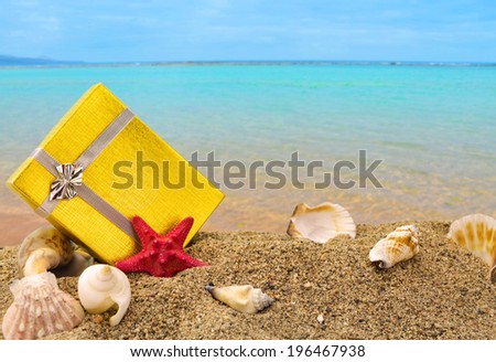 Gold gift box on sand with summer sea background
