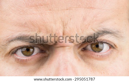 Upper part of males face closeup on angry eyes
