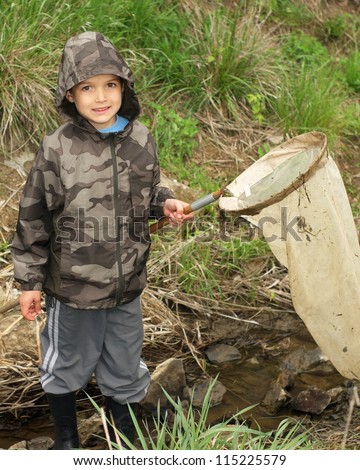 Boy with net and rain boots catching animals in a stream