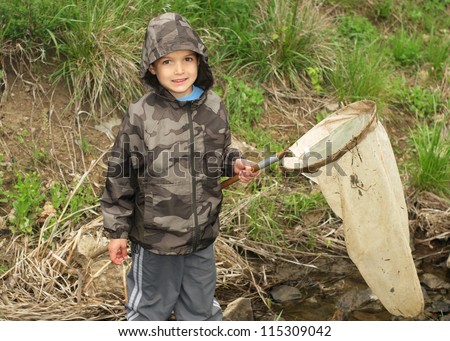 Child with net catching insects, fish, frogs and other animals in a stream