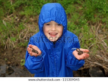 Child catching animals outside in the rain - holding snakes (Northern Watersnake and Graham\'s Crayfish Snake)