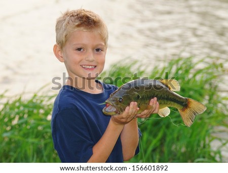 Kids fishing - a cute boy smiles as he holds a big fish he caught