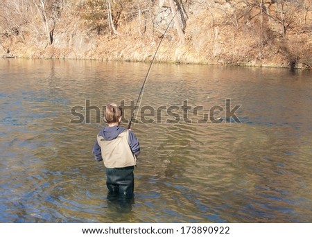 Children fishing - a boy fighting a big fish on a fly rod in a stream