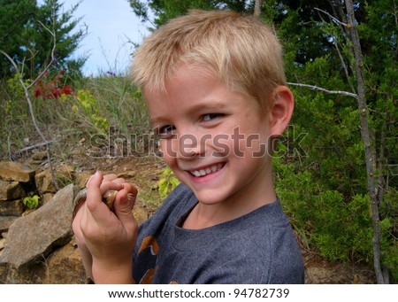Boy in the outdoors holding a large lizard (Great Plains Skink)