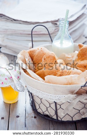 Fresh croissants with honey and milk for breakfast in a basket