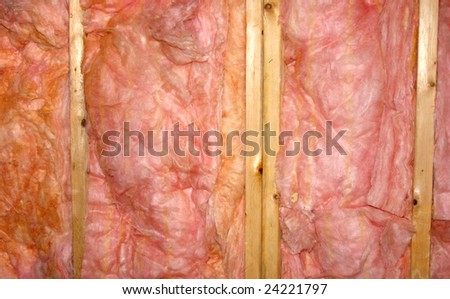 Pink insulation between wood studs.