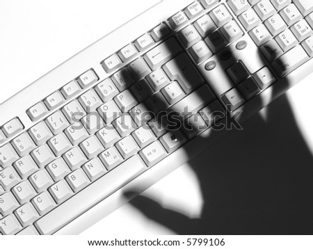 Shadow of a human hand over a computer keyboard