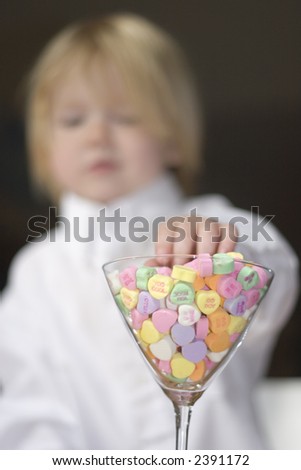 Small boy reaching for conversation hearts
