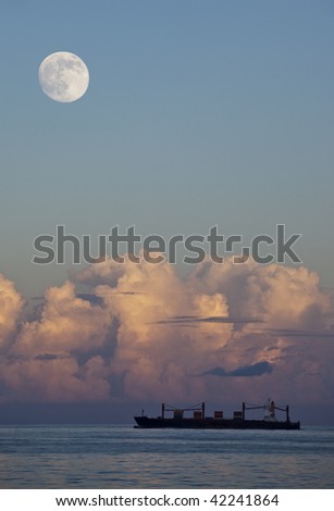 Sailing Container Ship, Vertical Aspect with Moon and clouds on horizon.