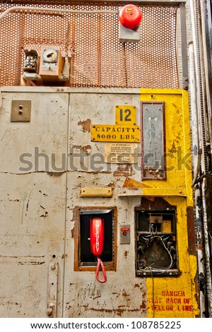 Controls, phone, and alarm bell. Freight elevator inside an abandoned factory.