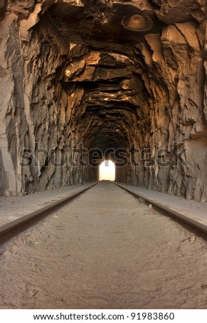 Light at the end of the tunnel. View inside a long railroad tunnel - bright light off in the distance.