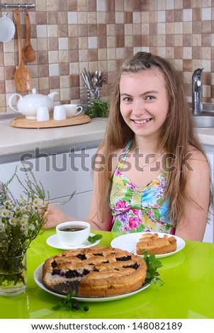 girl drinking tea with a cake in the kitchen