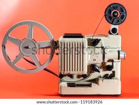 A vintage retro movie projector on a red background