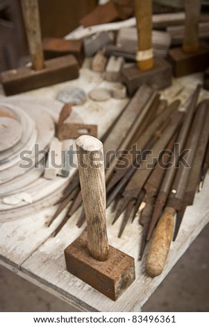 An old hammer resting on a table with other tools
