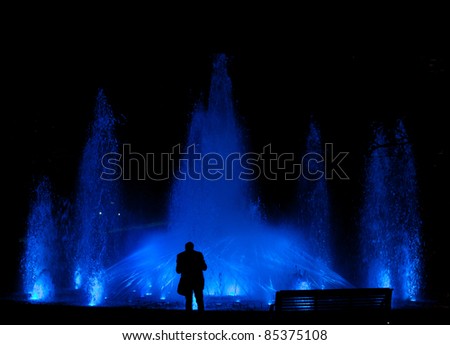 Male standing in front of a beautiful water feature fountain at night