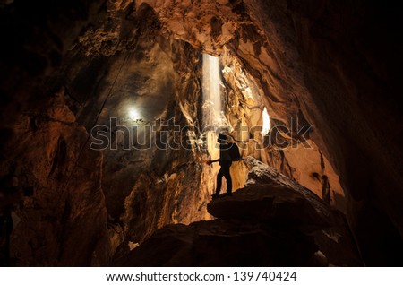 Sun Light in the cave with man standing on a rock