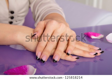 Woman hands with french manicure with crystals and rose petals