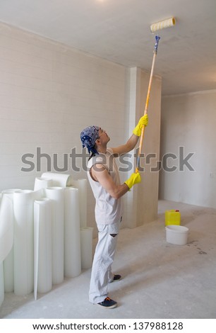 Young man - house painter worker painting ceiling with painting roller