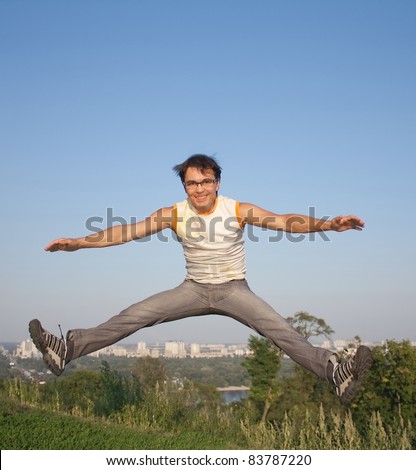 Happy young man jumping in air with arms extended on a city background