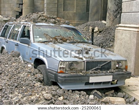 A car in amongst a lot of concrete rubble.