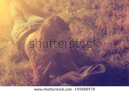Vintage photo of reading young woman in the grass at summer