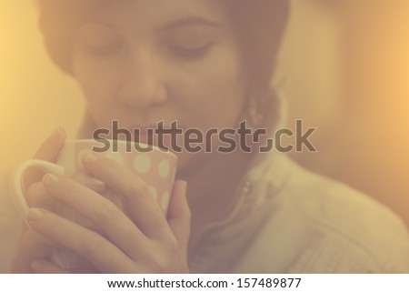 Vintage photo of tired woman drinking morning coffee or tea