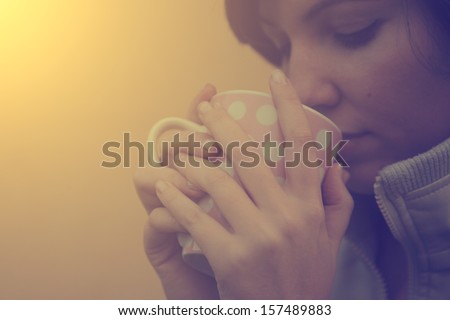 Vintage photo of tired woman drinking morning coffee or tea
