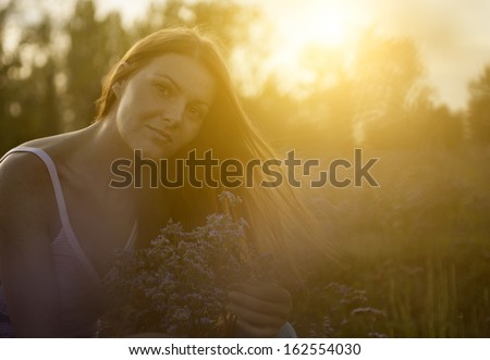 Young woman in sunset with bouquet of flowers