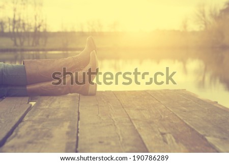 The girl's legs on pier in sunset